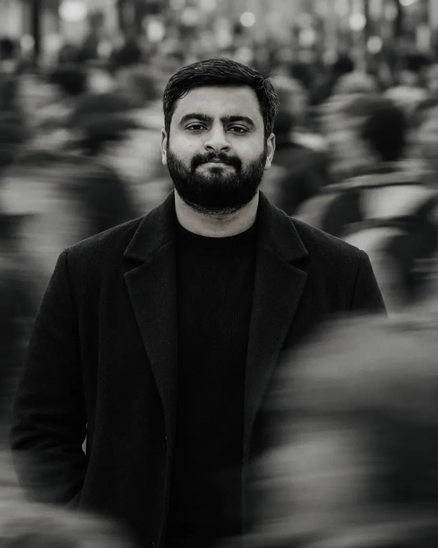 Syed Anas standing still in a moving crowd, black and white